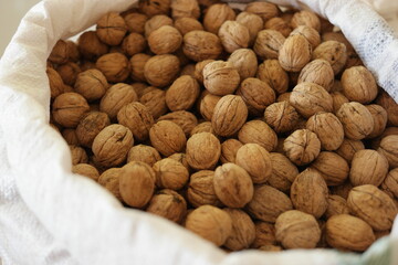 Big shelled walnuts close up. Heap of walnuts in sack at food market. Healthy eating concept.