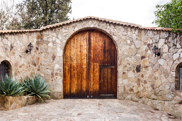 Fototapeta na wymiar Beautiful wooden door with a round high part, in a stone wall of a rural property.