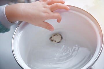 A little baby develops fine motor skills with small eggs - quail eggs. Helps mom in the kitchen. Preparing for Easter. Top view, copy space