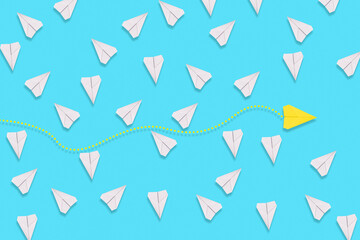 The concept of creativity and business. A yellow paper airplane flies among the white planes in search of a new solution. Blue background. Flat lay