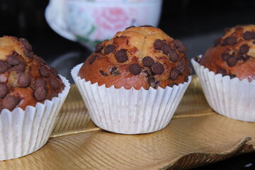 Magdalena con pepitas de chocolate con tetera de fondo.