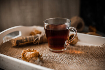 A cup of tea on a white tray, dried flowers, warm background