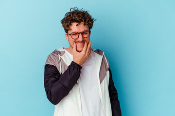 Young caucasian man wearing eyeglasses isolated on blue background doubting between two options.