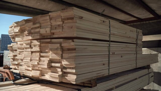 A forklift is loading wood planks into the truck. Transportation of wooden beams. Building materials for a house made of wood. Roof rafter system. Natural forestry planed products. Unloading pack.