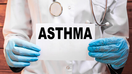 The doctor's blue - gloved hands show the word ASTHMA - . a gloved hand on a white background. Medical concept. the medicine