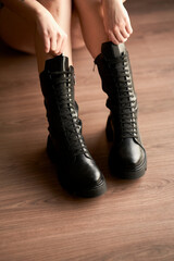 Women's feet in high black lace-up boots.