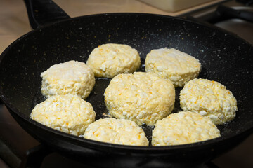 Many cottage cheese pancakes fried for breakfast in a black pan close-up