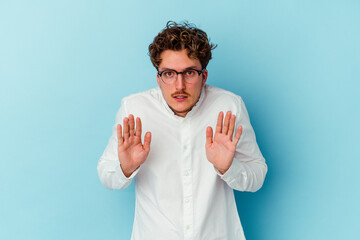 Young caucasian business man isolated on blue background rejecting someone showing a gesture of...