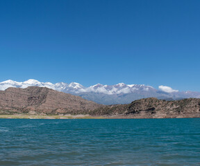 Obraz premium Lago azul con vistas a la cordillera de los Andes argentinos nevados durante el verano