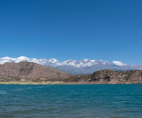 Fototapeta na wymiar Lago azul con vistas a la cordillera de los Andes argentinos nevados durante el verano
