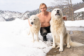 Man with a naked torso, two white dogs, snow