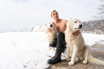 Man with a naked torso, two white dogs, snow