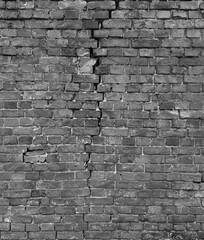 fragment of an old brick wall of a building with a crack, black and white texture, pattern or wallpaper