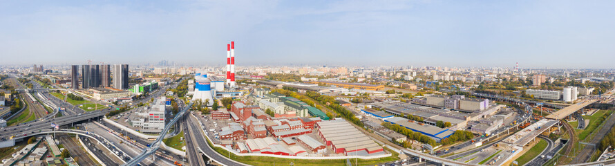 Power plant pipes and cooling towers in Moscow from above, automobile traffic and and construction of a new car overpass and interchange in the Moscow industrial zone near the automobile ring highway.