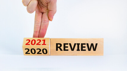 Business concept of new year 2021 review. Businessman flips a wooden cube and changes words 'review 2020' to 'review 2021'. Beautiful white background, copy space. Business, review 2021 symbol.