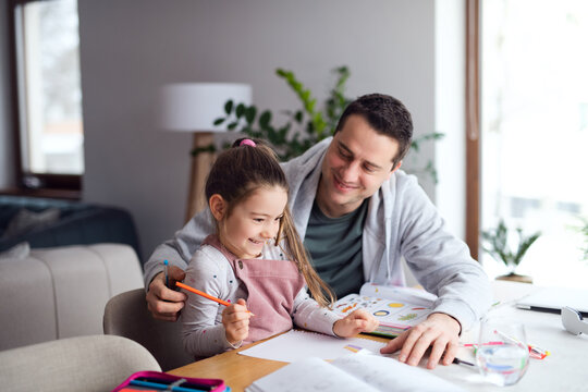 Father helping daugther with homework indoors at home, distance learning.