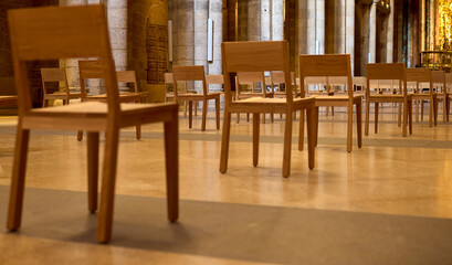 Several wooden chairs in perspective. They are placed in a large room