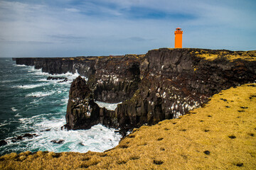 Svortuloft Lighthouse above the ocean with flying sea birds