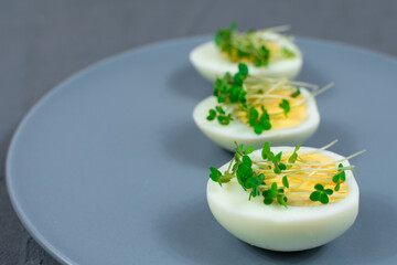 Close-up. Microgreens on eggs. Decorate the salad with microgreen leaves. Diet food. Boiled and fresh eggs next to fresh crispy herbs. Contemporary style salad.
