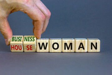 Housewoman or businesswoman symbol. Businessman turns cubes and changes the word housewoman to businesswoman. Beautiful grey background, copy space. Gender equality, businesswoman concept.
