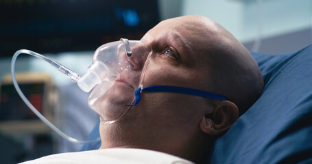 Sad cancer patient breathing oxygen in hospital