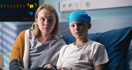 Woman and boy looking at camera in cancer clinic