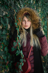 Fototapeta premium Portrait of a young girl from eastern Serbia. Posing by the wall covered with green leaves.