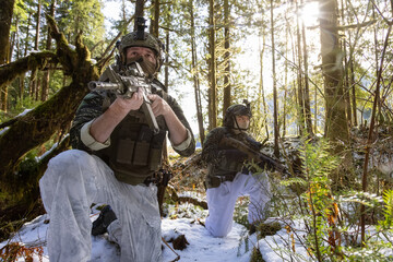 Army Man wearing Tactical Uniform and holding Machine gun in the Outdoor Rain Forest. Winter Warfare. Taken in British Columbia, Canada.