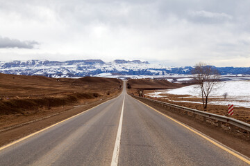 Caucasus Mountains, Panoramic view of the mountains on the horizon in winter day. On the way from Arkhyz to Dombay. Western Caucasus, Karachai-Cherkess, Russia. Serpentine road