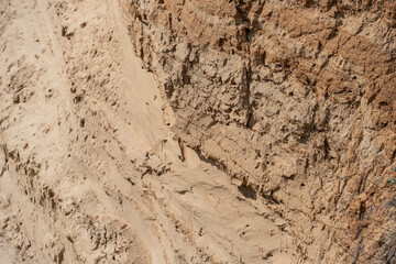 The steep slope of a sand mining quarry. Background and texture of sand. soil layers on a plot of the cut of the soil during a geological survey.