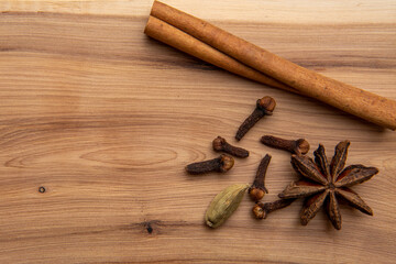 Cinnamon, cloves, star anise and cardamom pods on a wooden table.