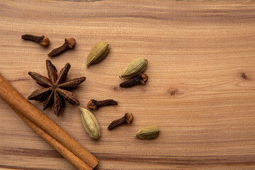 Cinnamon, cloves, star anise and cardamom pods on a wooden table.