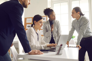 Young colleagues discussing a startup idea or a new business project by writing data to a laptop....