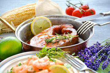 Salmon steak on the pan and prawns, lemon, limeta and vegetables