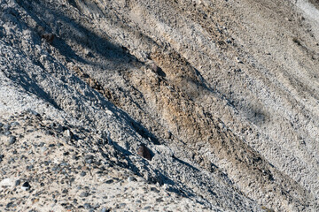 Geological cross-section of the soil. View of the sand mountain and various layers of soil. Sand quarry. Extraction of sand and stones.