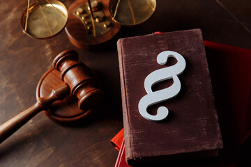 White paragraph symbol is on law books and gavel in courtroom.