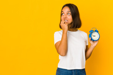 Young hispanic woman holding a megaphone relaxed thinking about something looking at a copy space.