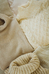 Warm woolen winter pullovers. Beige and brown. Minimalistic composition.