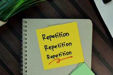 Repetition, Repetition, Repetition write on sticky notes isolated on Wooden Table.
