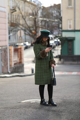 Portrait of beautiful woman using smart phone on the street . Woman in sunglasses looks into the phone street city.