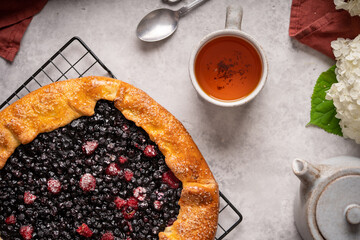 Homemade blueberry galette, tart on the table with tea and flowers. Top view. High quality photo