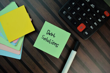 Debt Solution write on sticky notes isolated on Wooden Table.