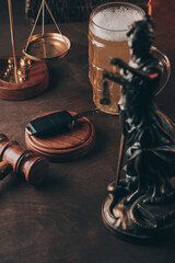 Glass of beer, car keys and judge gavel on a wooden table. Alcohol and car accidents concept. Vertical image.