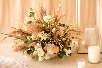 Decorations from dry beautiful flowers in a white vase on a beige fabric background