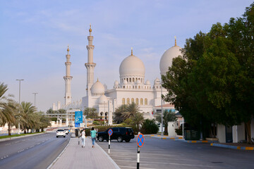 Fototapeta na wymiar Sheikh Zayed Mosque against the blue sky and two girls going there