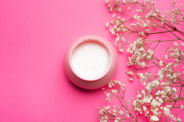 Cream for face in flowers . Face cream on a pink background. Skin care. The beauty industry. Copy space. White flowers. Article about the right choice of cream. Selection of the cream. Spa treatments.