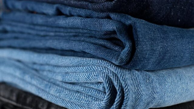 denim. stack of folded jeans blue, black, light blue, close up. Many pairs of denim trousers