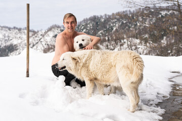 Man with a naked torso, two white dogs, snow