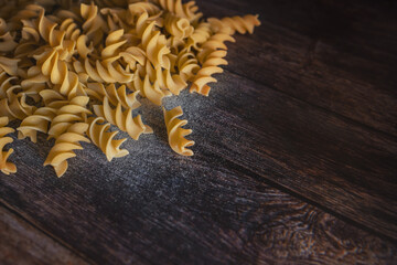 A pile of Italian pasta spindles lying on a wooden table.