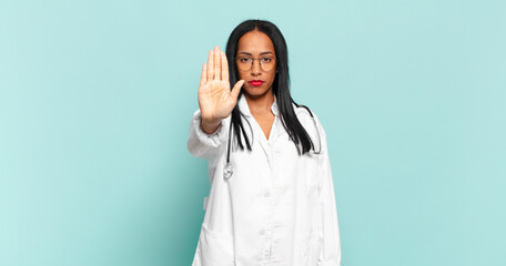 young black woman looking serious, stern, displeased and angry showing open palm making stop...